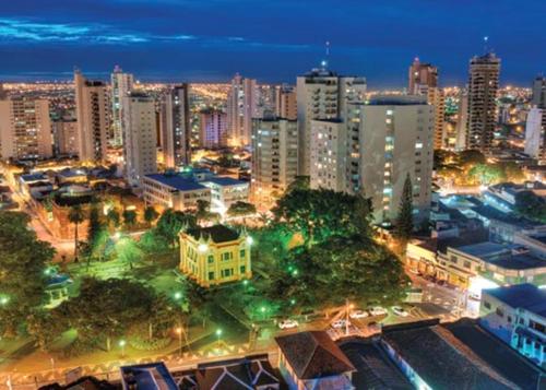 uma cidade iluminada à noite com edifícios e árvores em Loft Familiar BR-Aeroporto 4 em Uberlândia