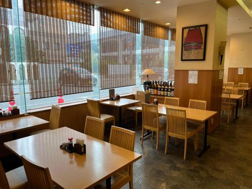 un restaurant avec des tables et des chaises en bois ainsi que des fenêtres dans l'établissement Hotel Alpha-One Niigata, à Niigata