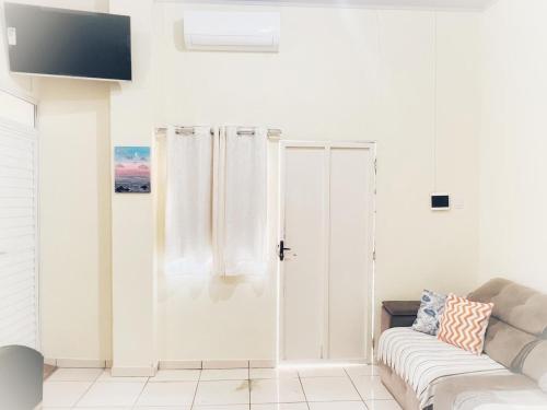 a white living room with a couch and a window at Loft Familiar BR-Aeroporto 4 in Uberlândia