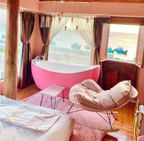 a bathroom with a pink tub and a bed and a window at Oceanside Villa Phuquy Island in Cu Lao Thu