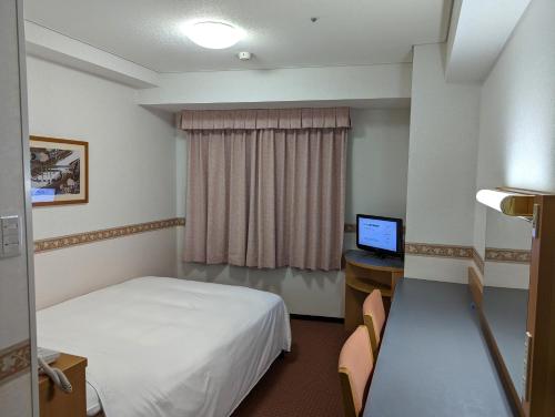 横浜市にあるホテルアルファーワン横浜関内のベッド、デスク、コンピュータが備わるホテルルームです。