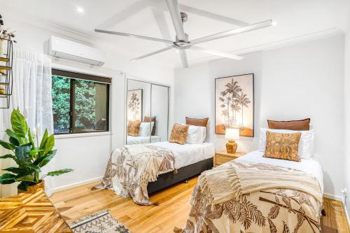 sypialnia z 2 łóżkami i oknem w obiekcie The Orchard House - Luxury Tropical Villa w mieście Redlynch