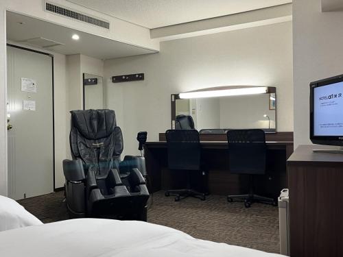 米沢市にあるホテルアルファーワン米沢の椅子、デスク、コンピュータが備わる客室です。