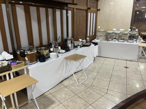 ein Zimmer mit weißen Tischen mit Essen drauf in der Unterkunft Hotel Alpha-One Yonezawa in Yonezawa