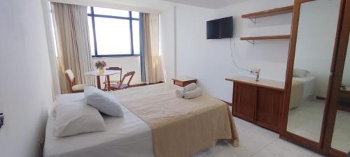 1 dormitorio con cama, espejo y mesa en Hotel sol vitória Marina, en Salvador