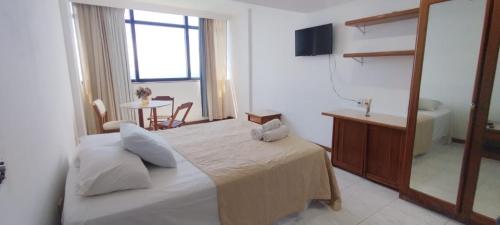 a bedroom with a bed and a mirror and a table at Hotel sol vitória Marina in Salvador