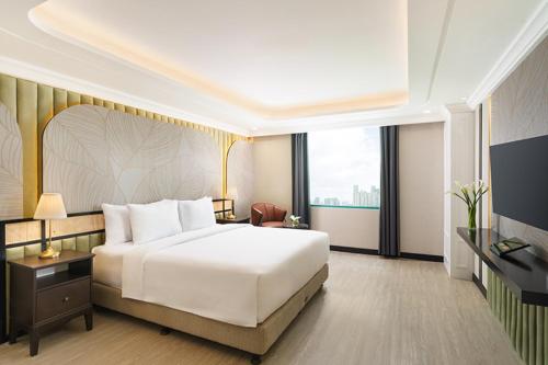 a bedroom with a white bed and a large window at Tavia Heritage Hotel in Jakarta