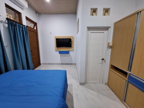1 dormitorio con 1 cama azul y TV en Say Villa, en Kejayan