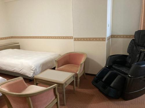 um quarto de hotel com uma cama e uma cadeira em Hotel Alpha-One Iwaki em Iwaki