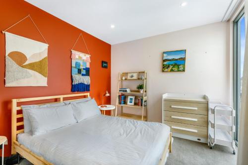 een slaapkamer met een oranje accentwand en een bed bij Quirky, Spacious & Sophisticated 2-Bed in St Kilda in Melbourne