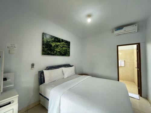 a bedroom with a white bed and a bathroom at Canggu 77 Guest House in Canggu