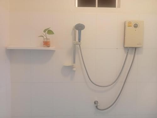 a shower in a white bathroom with a hose at Happy Home Guest House in Ban Phe