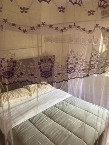 a bedroom with a canopy bed with white curtains at Kampala Comfort living in Kampala