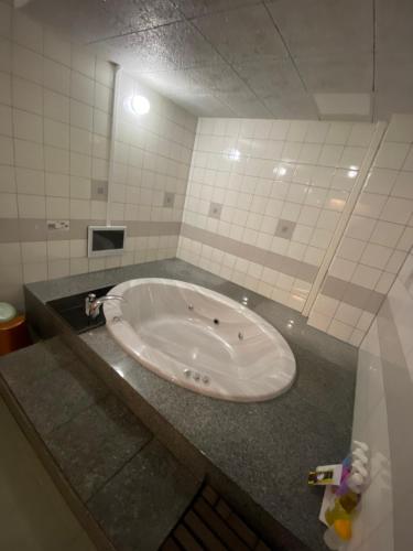 een badkamer met een ligbad en een wastafel bij ラブホテル tabasaサンレモ in Fukuoka
