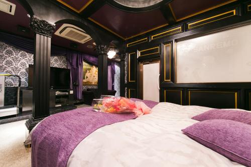 een slaapkamer met een groot bed met paarse lakens bij ラブホテル tabasaサンレモ in Fukuoka