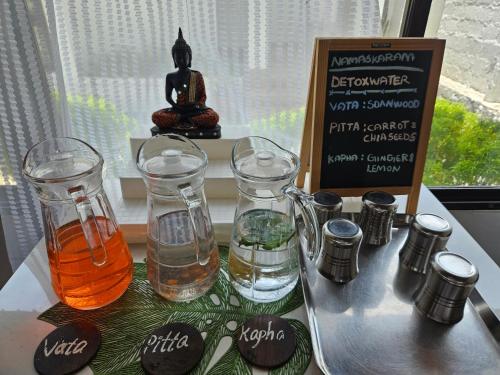 a tray with two glasses of water and a sign at Veda5 Ayurveda Living Village in Trichūr