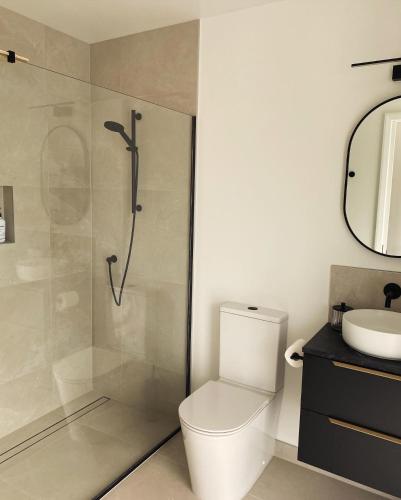 a bathroom with a shower and a toilet and a sink at Ahuru House in Mangawhai