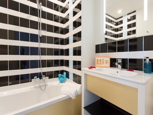 een badkamer met een bad en een wastafel bij Privilège Appart-Hôtel Domaine De Mai - parking gratuit in Mougins