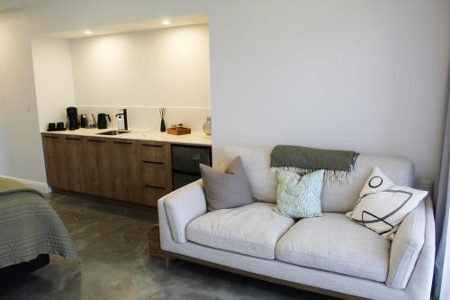 a living room with a couch and a kitchen at Ahuru House in Mangawhai