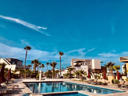 a pool at a resort with palm trees and buildings at LUX 3 MASTER BDROOM ON SANDY BEACH w NO CLEAINING FEE in Puerto Peñasco