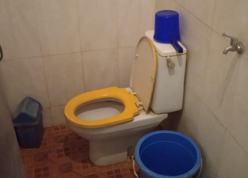 a bathroom with a toilet with a yellow seat at Griya Istana 1 in Solo