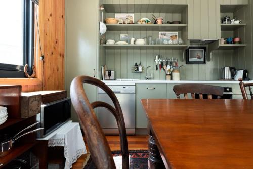 a kitchen with a wooden table and chairs and a table and a counter at Rustic Barn by the Bay in Low Head