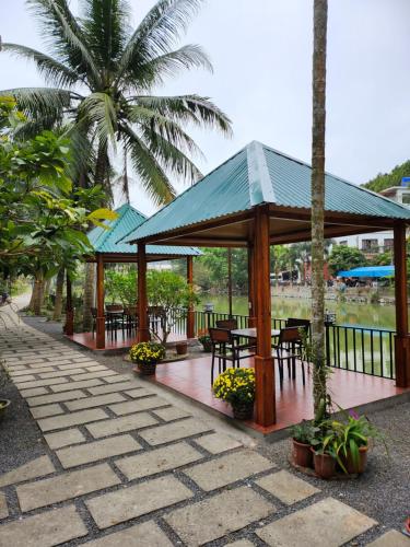 a pavilion with tables and chairs and palm trees at 2Stones Cát Bà Homestay in Cat Ba