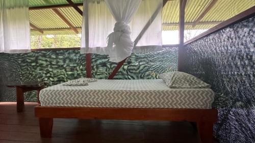 a bedroom with a bed with a canopy and a window at Ecoturístico La Tarde in Puerto Jiménez