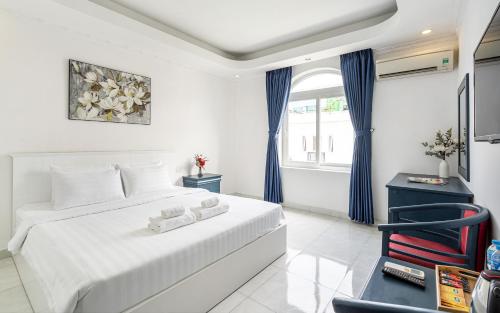 een witte slaapkamer met een bed en een stoel bij La Casona Boutique Hotel in Ho Chi Minh-stad
