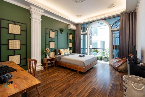 1 dormitorio con paredes verdes, 1 cama y 1 mesa en HOLO LE THANH TON SAIGON Serviced HomeStay, en Ho Chi Minh