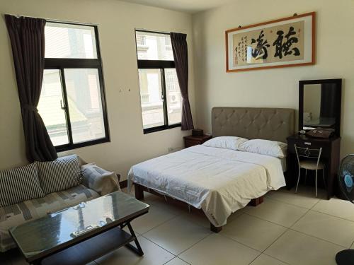 a bedroom with a bed and a couch and a table at Yan Gui Lai B&B in Hengchun South Gate