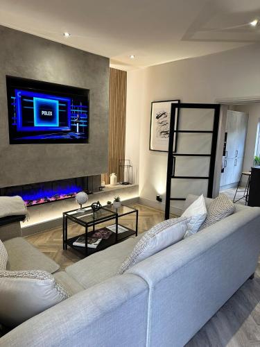a living room with a white couch and a tv at Stunning Town Center Cottage with hot tub in Morpeth