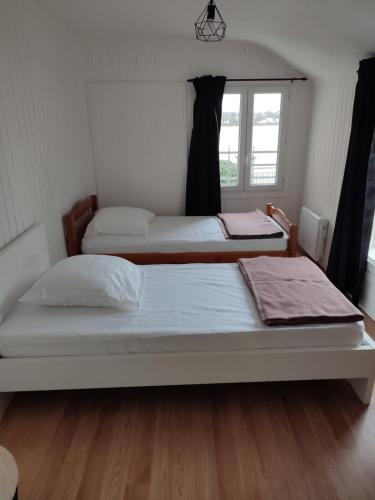 1 dormitorio con 2 camas y ventana en Location petite maison, en Quillebeuf-sur-Seine