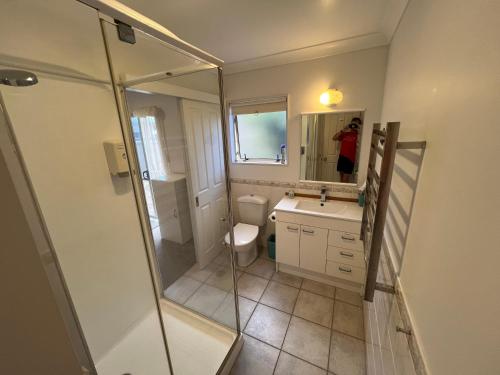 a bathroom with a shower and a toilet and a sink at Beachside Bliss in Tauranga