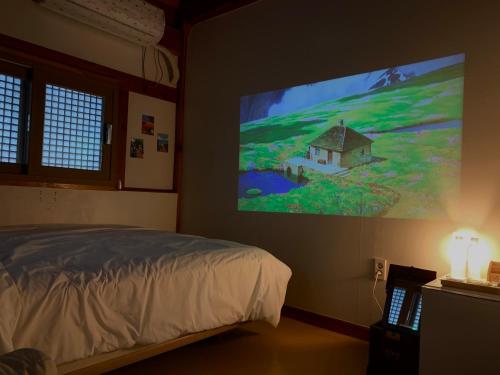 sypialnia z łóżkiem i dużym telewizorem na ścianie w obiekcie Hanji Gguljam w mieście Jeonju