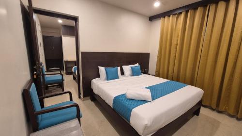a bedroom with a bed and a chair in it at Hotel JANAS in Tirupati