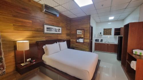 a bedroom with a white bed and wooden walls at Hotel Casa Miller in Panama City