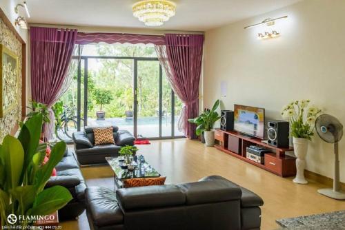 sala de estar con sofá de cuero y TV en Flamingo Villa Owner_ Villa in Đại Lải Vĩnh Phúc, en Ngọc Quang