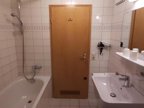een badkamer met een deur naar een bad en een wastafel bij Property in Bayrischzell in Bayrischzell