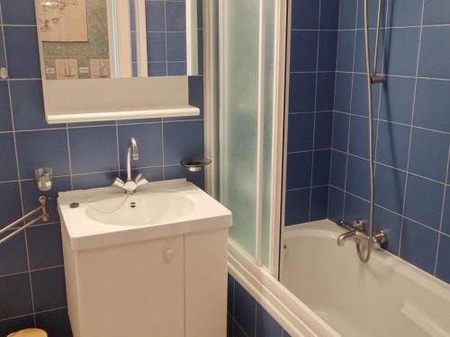 W wyłożonej niebieskimi kafelkami łazience znajduje się umywalka i wanna. w obiekcie Sirenuse I 0404 with beautiful sea view w mieście Nieuwpoort