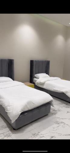 2 bedden in een kamer met witte lakens bij سي بريز in Quţuf al Mişrī