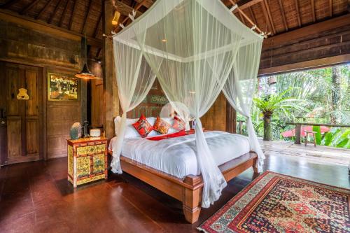 een slaapkamer met een hemelbed bij Anam Cara Villa in Ubud