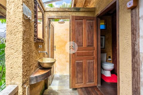 een badkamer met een houten deur, een wastafel en een toilet bij Anam Cara Villa in Ubud