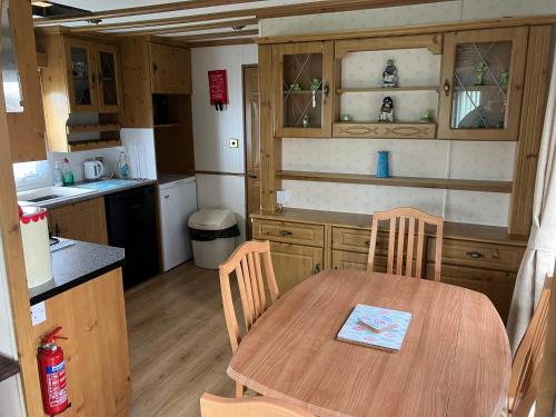 uma pequena cozinha com uma mesa de madeira e cadeiras em Spacious caravan with DG, CH & veranda em Skegness