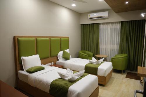 two beds in a hotel room with green accents at Mount Grande "formerly known as Miot Grande" in Chennai