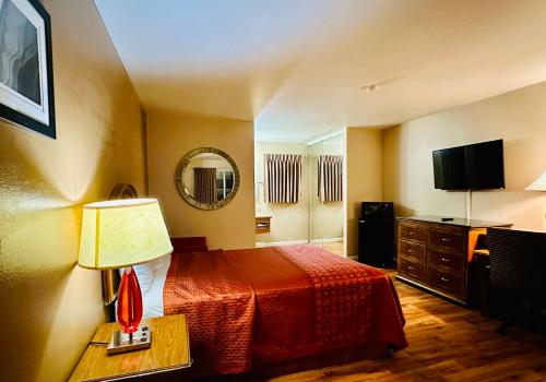 Habitación de hotel con cama y espejo en Franciscan Inn Motel, en Vista