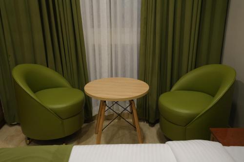 two green chairs and a table in a room at Mount Grande "formerly known as Miot Grande" in Chennai