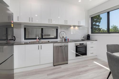 a kitchen with white cabinets and stainless steel appliances at Chic 2-Bed Home with Backyard, BBQ & Parking in Phillip