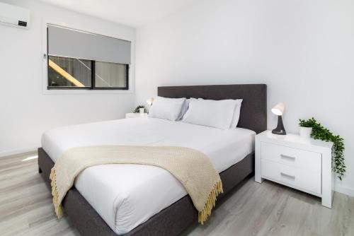 um quarto branco com uma cama grande e uma janela em Chic 2-Bed Home with Backyard, BBQ & Parking em Phillip