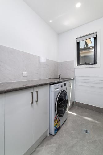 a white laundry room with a washing machine at Chic 2-Bed Home with Backyard, BBQ & Parking in Phillip